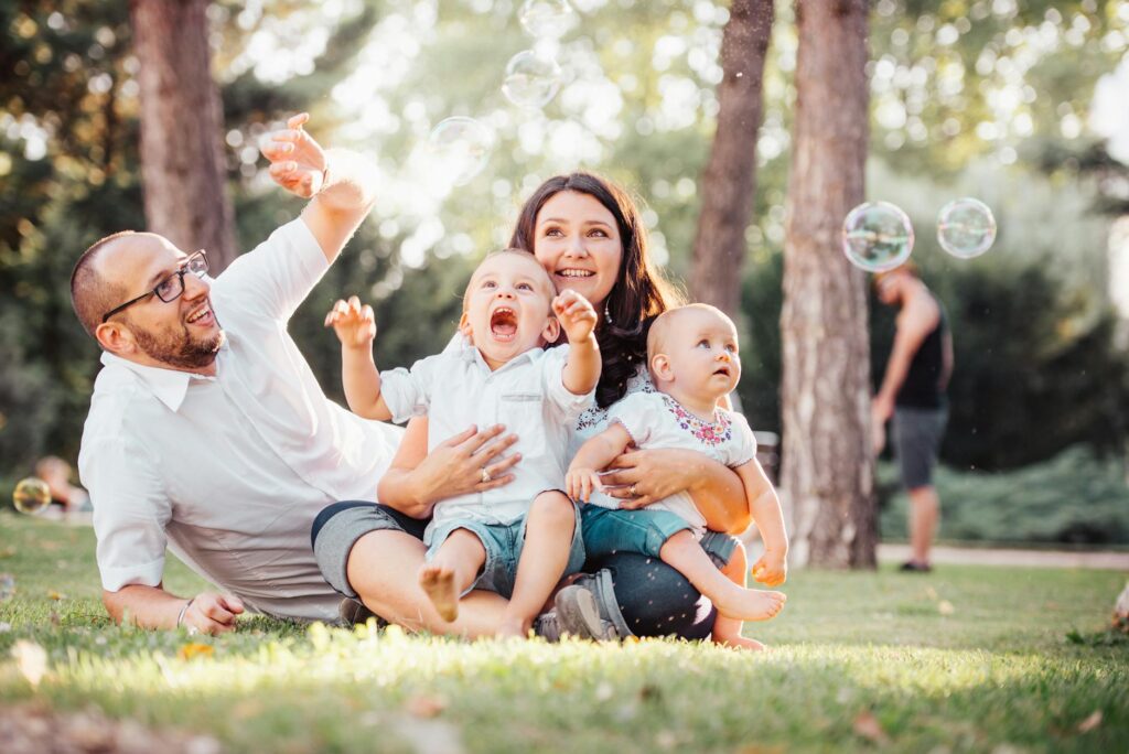 Familienversicherung 25 – Erster Job & Steuern (Symbolbild: Fröhliche Familie genießt einen sonnigen Tag im Park und spielt mit Seifenblasen.)