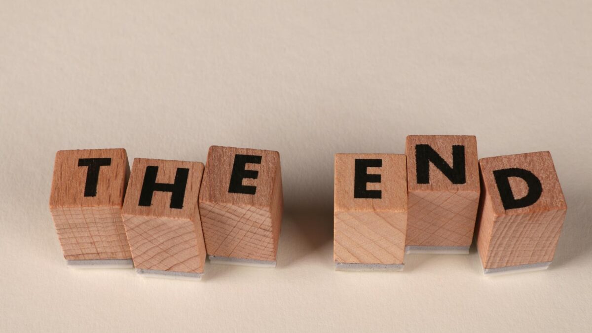 Familienversicherung ende – Erste eigene Versicherung (Symbolbild: Auf einem schlichten beigen Hintergrund sind Holzklötze so angeordnet, dass sie das Wort „The End“ buchstabieren und so einen Abschluss symbolisieren.)