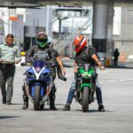 Führerschein kosten – Erstes Auto & Führerschein (Symbolbild: Motorradfahrer mit Helmen interagieren an einem Grenzkontrollpunkt im Freien mit einem Polizisten.)