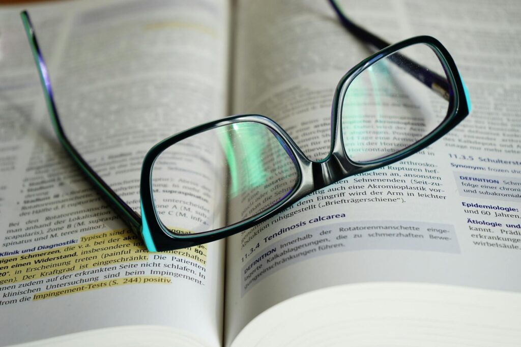 Lohnabrechnung verstehen – Erster Job & Steuern (Symbolbild: Brillen Mit Schwarzen Rahmen Auf Buch)
