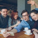 Privathaftpflicht junge erwachsene – Erste eigene Versicherung (Symbolbild: Eine Gruppe von Freunden hat Spaß, trinkt Kaffee und macht ein Selfie in einem Café.)