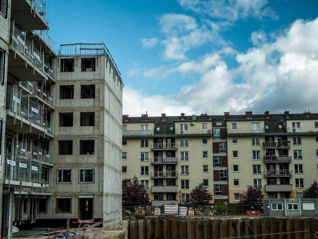 übergabeprotokoll wohnung – Erste eigene Wohnung (Symbolbild: Baustelle neben Wohnhäusern unter blauem Himmel.)