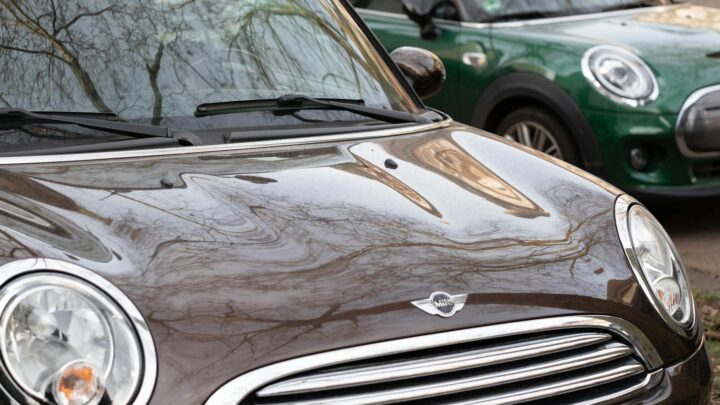Carsharing vs eigenes auto – Erstes Auto & Führerschein (Symbolbild: Nahaufnahme von zwei Mini Cooper-Autos, die die städtische Umgebung widerspiegeln und das moderne Design betonen.)