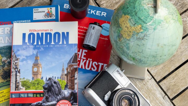 Reise stornieren – Erste Reise allein (Symbolbild: Flaches Layout mit London-Reiseführer, Vintage-Kamera und Globus, ideal für Reisethemen.)